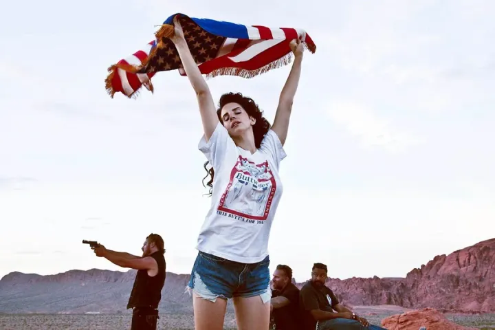 Lana Del Rey in the "Ride" video, dancing with an American flag and wearing red, white and blue while middle-aged (mostl